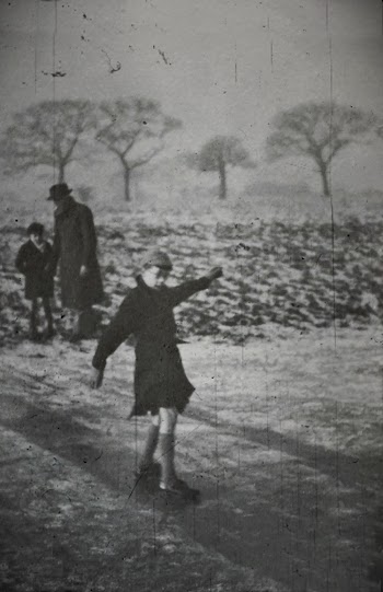 A Stained Monochrome Old Photo Of Child Playing With An Adult And A Kid On The Background Outdoor In Winter