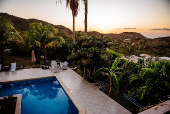 A Swimming Pool Surrounded By Trees With The View Of Mountains