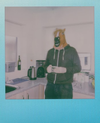 A Tall Person Wearing A Horse Mask Holding A Mug In The Kitchen
