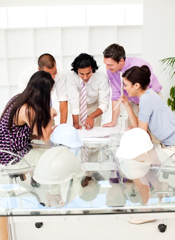 A team of architects at the meeting looking at blueprints in the office