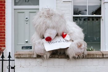 A very large rain-soaked teddy bear found sitting on a wall outside a house in London.