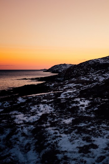 A view of the Duncan's Cove coastline line trail at sunset. You can see the bomb shelter from WWII, and a lighthouse in the distance.