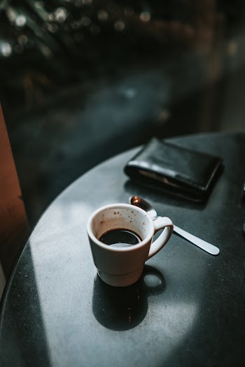 A Wallet and White Ceramic Mug Filled With Coffee on a table 