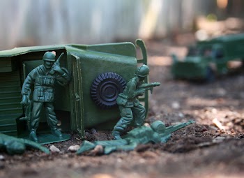 A war scene created with green plastic toy army men. Four of the...