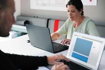 A woman and man both staring at their laptop screens.