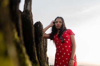 A Woman In A Floral Dress Leans On A Wall