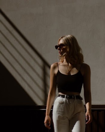 A Woman in Black Tank Top Wearing Sunglasses while Looking Over Shoulder