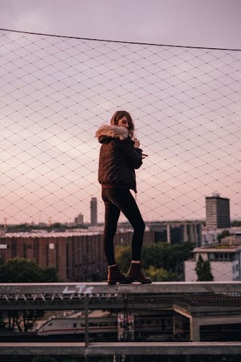 A woman poses in front of rooftops wearing a Timberland parka and Timberland boots
