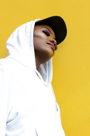 a woman posing in a white hoody sweater with her eyes closed