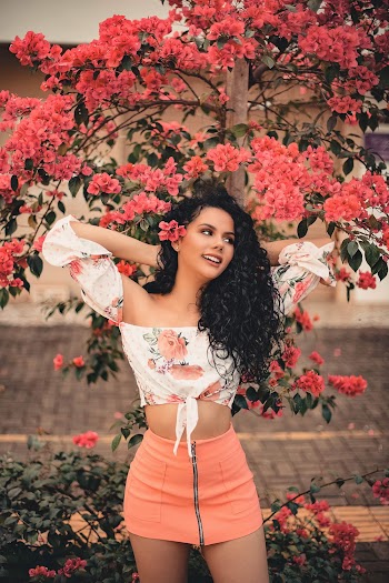 A Woman Posing With  Flowers Bearing Tree As Background