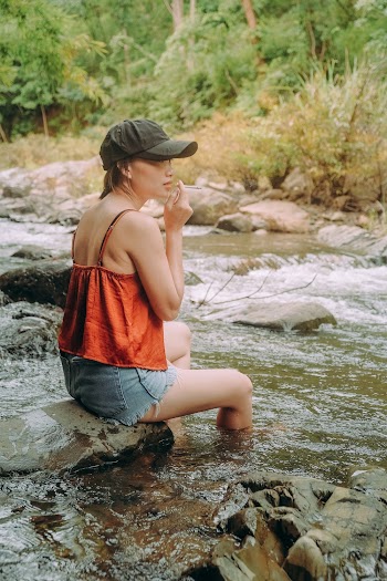 A Woman Sitting On A River Rock