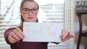 A Young Blonde Female With Glasses Holding Up A Piece Of Paper ...