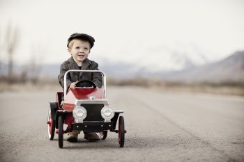 A young boy driver is out for a drive in his pedal car. Vintage tone.