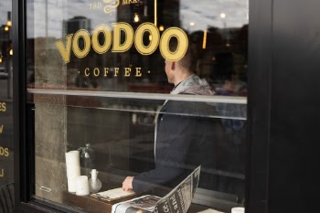 A young man having a conversation in a coffee shop while looking at the menu. 
