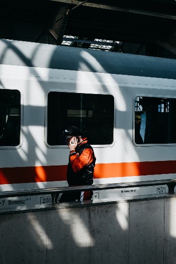 A young man passes through the sunlight and shadows on a waiting train at Berlin-Ostbahnhof. 