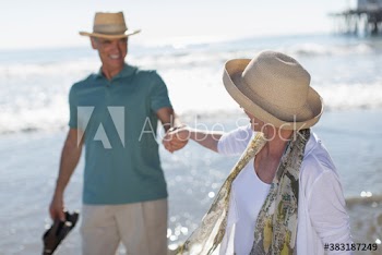 Active senior couple holding hands on sunny ocean beach