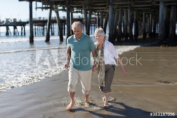 Active senior couple wading in sunny ocean surf