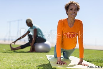 Active senior woman practicing yoga on sunny lawn