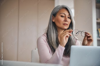 Adult gray hair woman sitting at the desk in room indoors