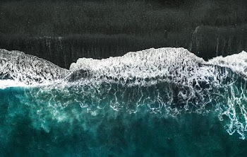 Aerial Photo of Body of Water Crashing into Shore