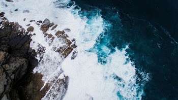 aerial photo of body of water crashing stone