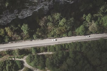 aerial photo of gray concrete in the middle of forest with two cars