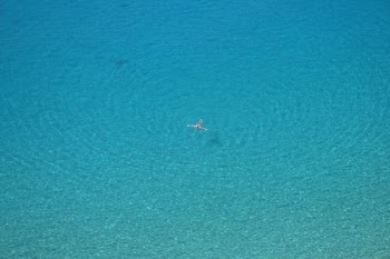aerial photo of person swimming on body of water during daytime