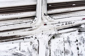 aerial photo of red vehicle on snow covered road crossing at daytime