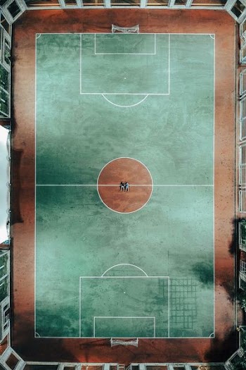 aerial photo of two people lying on green and brown sports court