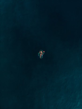 Aerial Photo of Woman Lying on Inflatable Floater in the Middle of Ocean