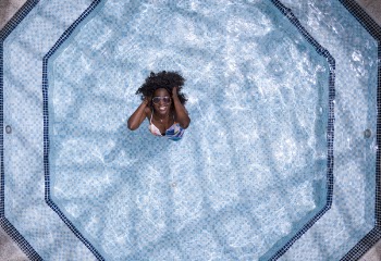 Aerial Photo of Woman Wearing White and Blue Bikini Top Standing on Swimming Pool