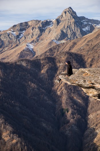 Aerial Photography Man Sitting on Mountain Cliff