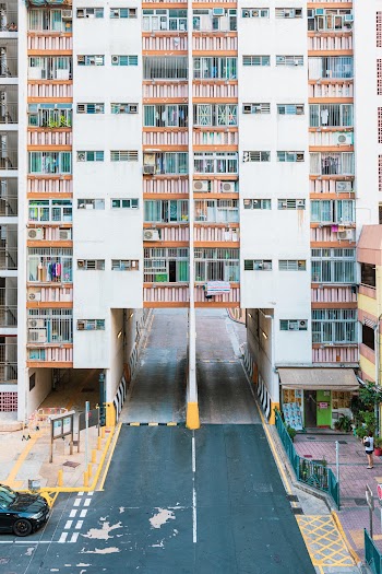 Aerial Photography of Black Vehicle on Road and Person Standing Near High-rise Buildings