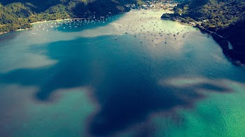 Aerial Photography of Boats Near Body of Water Beside Mountain