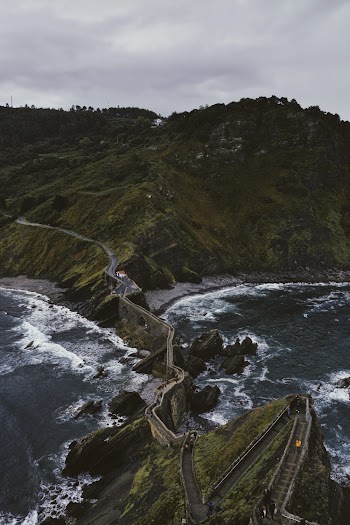 Aerial Photography of Bridge and Mountain Viewing Body of Water Under Grey Skies