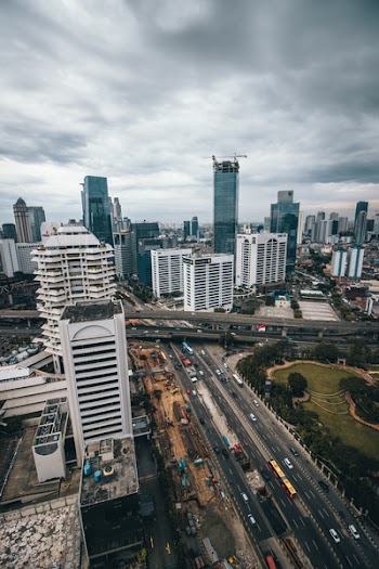 Aerial Photography of Building and Vehicle Passing on Road Under Gloomy Sky