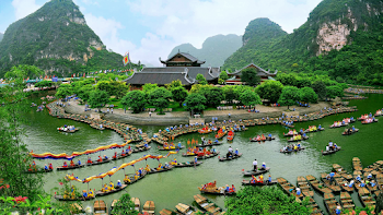 Aerial Photography of Building Surrounded With Body of Water With Boats Across Tree Covered Hills