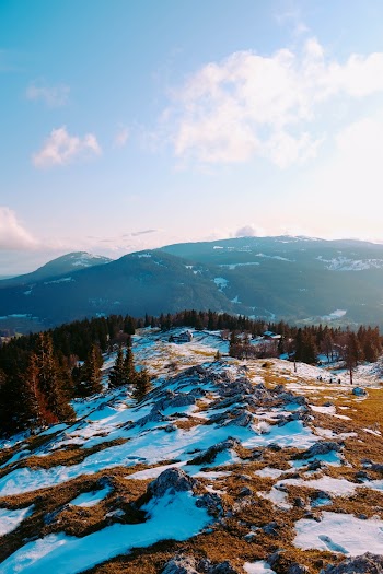 Aerial Photography of Field Covered With Snow Viewing Mountain Under White and Blue Sky