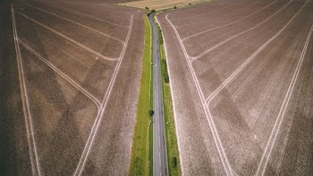 aerial photography of gray concrete road top between brown field during daytime