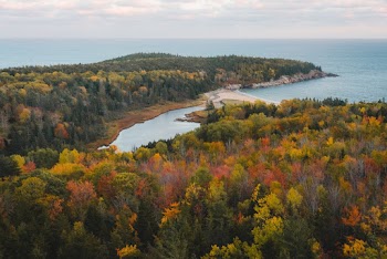 Aerial Photography of Mountain With Tall Trees Viewing Calm Sea Under White and Blue Skies