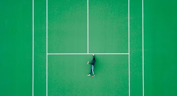 aerial photography of person lying on tennis court