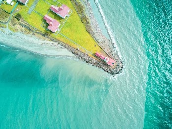 aerial photography of pink house at the edge of land near body of water