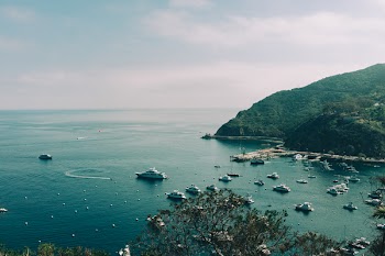 Aerial Photography of Ships on Calm Body of Water Beside Mountain