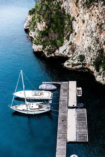 aerial photography of three yachts docking on wooden dock beside island