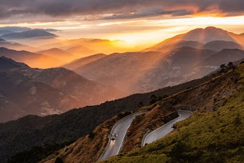 Aerial Photography of Vehicle on Road Viewing Mountain Under Yellow Sky