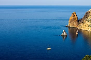 aerial photography of white ship on sea near rock formations under blue sky during daytime