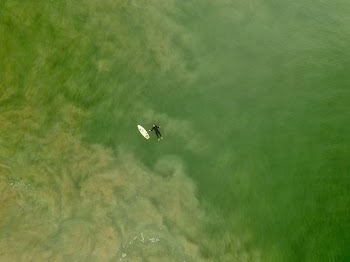 aerial photography person floating at sea beside white board at daytime