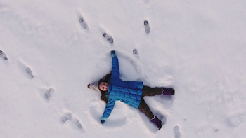 Aerial shot of a little girl making a snow angel in the snow, 4K ...