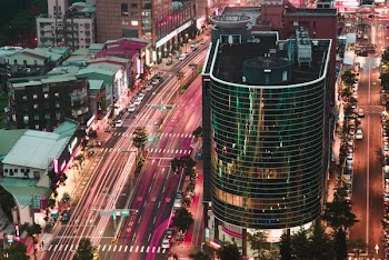 aerial time-lapse photography of vehicle cruising on road at either side of buildings during night time