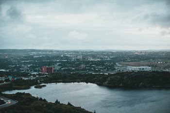 Aerial View of a Lake Near a City Under a Cloudy Sky